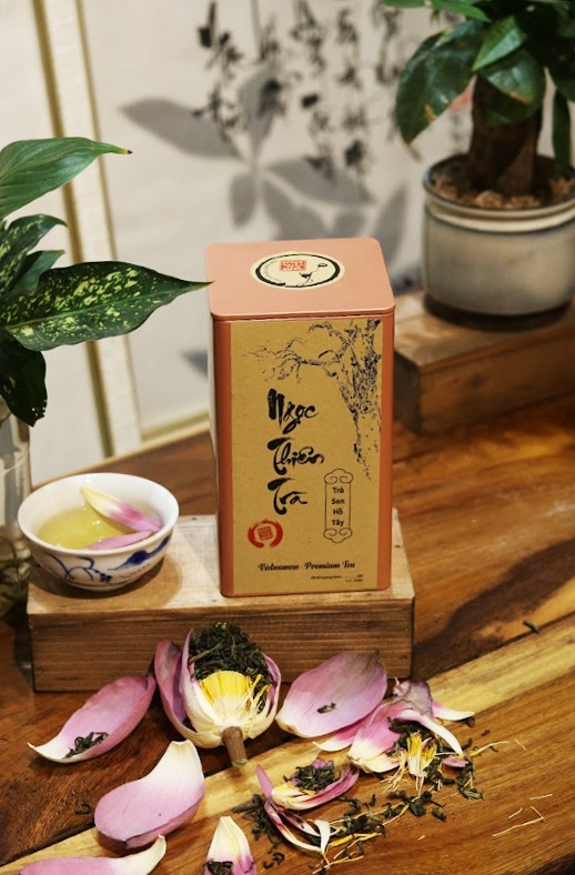 Hộp trà sen Tây Hồ cạnh chén trà, cánh sen và gạo sen